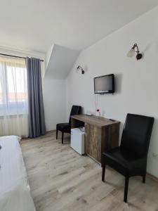 a room with a bed and a desk and two chairs at Pensiunea Roua in Piatra Neamţ