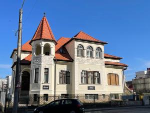 un edificio con una torre y un coche estacionado frente a ella en Vila Mărioara, en Sibiu 13 fotos más