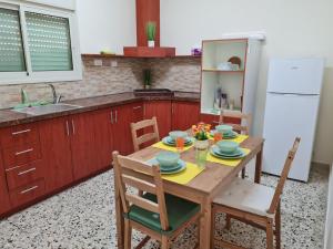 Rizik's Guest House في الناصرة: مطبخ مع طاولة خشبية مع كراسي وثلاجة بيضاء