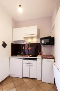 a kitchen with white cabinets and a stove top oven at Observatoire in Nice