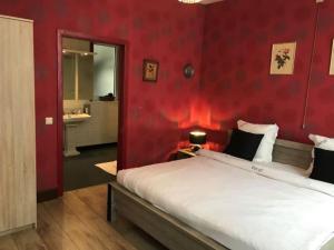 a bedroom with a red wall with a large bed at B&B Verdi in Bruges