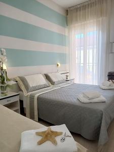 1 dormitorio con 2 camas y una ventana con estrella de mar en Hotel Cristoforo Colombo, en Cesenatico