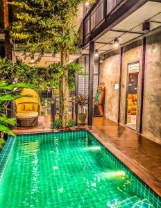 an indoor swimming pool with green water in a house at Exclusive access to the whole garden. in Bangkok