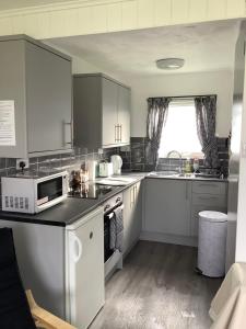 a kitchen with white cabinets and a white microwave at 125 Sundowner in Hemsby