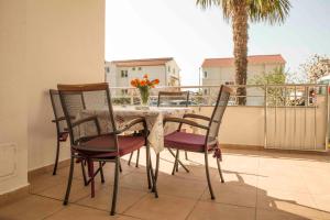 a dining table and chairs on a balcony with a palm tree at Apartment Zora in Vodice