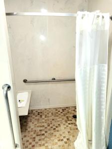 a bathroom with a shower with a shower curtain at Best Price Motel & Suites in Orange