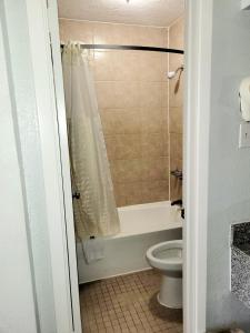 y baño con bañera, aseo y ducha. en Best Price Motel & Suites en Orange