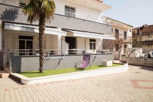 a purple chair sitting next to a palm tree in front of a house at Apartment Zora in Vodice