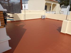 a balcony with a red floor and a white wall at Maré Beach in Monte Gordo