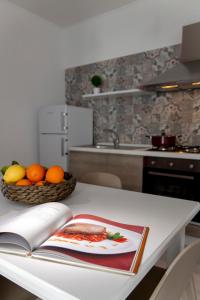 un tavolo da cucina con un libro e un cesto di frutta di CasaTrapani Rooms & Apartments a Trapani