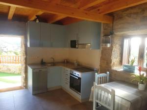 a kitchen with white cabinets and a table and a table and chairs at A Casiña do Xastre in Pontevedra