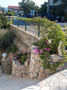 a garden with flowers and a stone wall at Apartman Franelić Banjol in Banjol