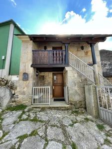 a stone house with a wooden door and a balcony at Casa Casoa in Piornedo