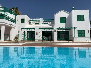 una casa con piscina frente a ella en Apartamentos Las Palmeras I, en Puerto del Carmen