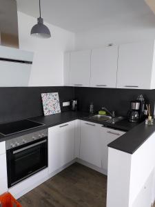 a kitchen with white cabinets and black counter tops at Ferienwohnung Langgöns in Langgöns