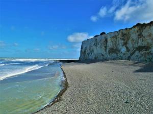 a sandy beach with a cliff next to the ocean at Gite Le Minile in Béthencourt-sur-Mer