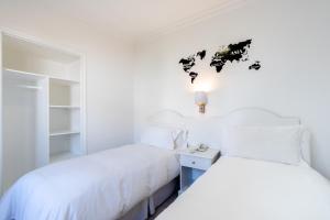プンタ・デル・エステにあるHotel Romimar 3* Supの白い壁のベッドルーム1室(ベッド2台付)