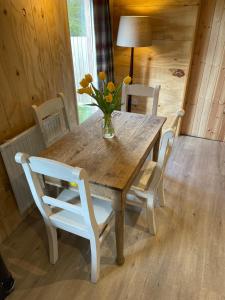une table en bois avec des chaises et un vase de fleurs. dans l'établissement Keepers Cottage, à Ipswich