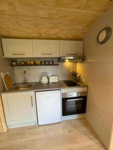 una piccola cucina con armadietti bianchi e un orologio di Keepers Cottage a Ipswich