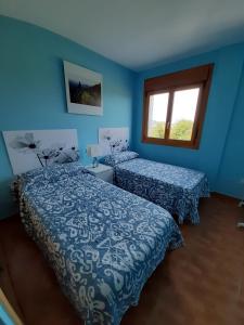 een blauwe kamer met 2 bedden en een raam bij Lugomar in Reinante