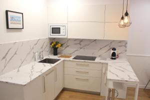a white kitchen with a sink and a counter at CENTRAL NEAR SEA - by SanSebastianApartments·es in San Sebastián