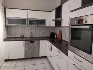 una cocina con armarios blancos y electrodomésticos de acero inoxidable en Gute Laune, en Friedrichshafen
