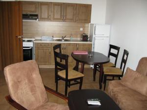 a kitchen with a table and chairs and a kitchen with a refrigerator at Krasi Apartments in Zornitsa Complex in Stoykite