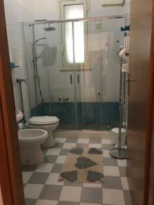 een badkamer met 2 toiletten en een glazen douche bij Apartment La Conchiglia in Menfi