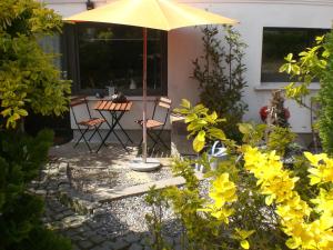 een patio met een tafel en stoelen en een parasol bij Zur Weide in Boltenhagen