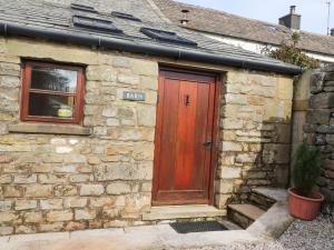 a stone house with a red door and a window at Usherwoods Barn in Lancaster