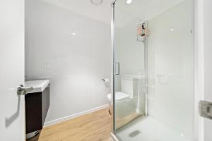 uma casa de banho com um WC e uma porta de duche em vidro. em Stylish Brand New Apartment - 7 Minute walk to Town em Queenstown