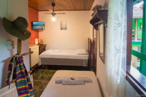 a small room with two beds and a television at Pousada Taquinha Paraty in Paraty