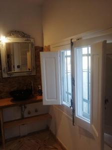 a bathroom with two windows and a sink and a mirror at La corrala in Belmonte de Tajo