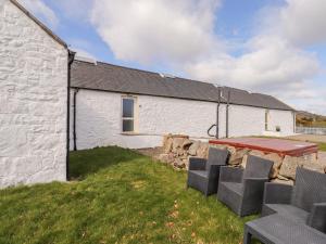 a white building with a table and chairs in front of it at Shetland Cottage in Dalbeattie