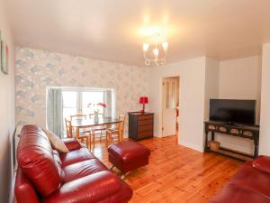 a living room with a leather couch and a table at Shetland Cottage in Dalbeattie