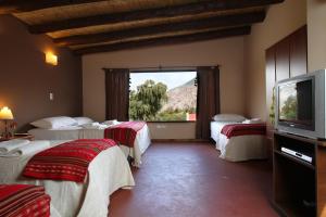 um quarto de hotel com três camas e uma televisão em Mirador Del Virrey, Cabañas Boutique em Purmamarca