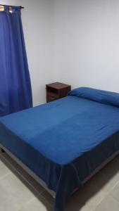 1 dormitorio con cama azul y cortina azul en CABAÑAS HUITRU en General Alvear