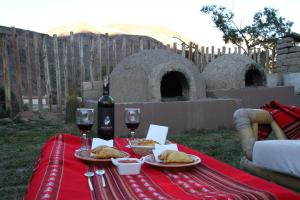 een tafel met twee borden eten en wijnglazen bij Mirador Del Virrey, Cabañas Boutique in Purmamarca