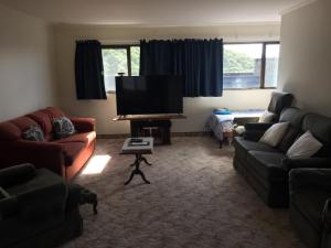 a living room with couches and a flat screen tv at Dons Place in Waikawa