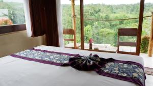 a bed with a bow on it in front of a window at Padi Bali Jatiluwih by Manara in Jatiluwih