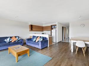 uma sala de estar com dois sofás azuis e uma mesa em Apartment 29 Pacific Apartments em Lorne