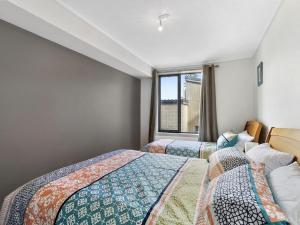 two beds in a room with a window at Apartment 29 Pacific Apartments in Lorne