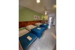 Habitación con 2 camas y sofás azules. en Memorália Suítes, en Arraial do Cabo