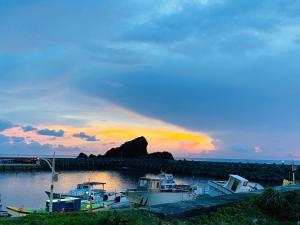 a group of boats docked at a dock with a sunset at DoDoWu Homestay in Lanyu