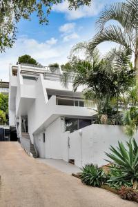 a white building with stairs and palm trees at Noosa Views in Noosa Heads