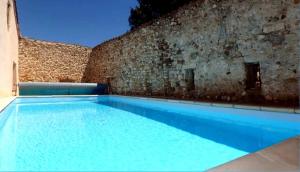a large blue swimming pool next to a brick wall at Le gite de Modestine in Boucoiran-et-Nozières