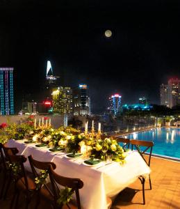胡志明市Happy Life Grand Hotel & Rooftop Skybar的屋顶上摆着一张长桌，上面放着鲜花和蜡烛。 更多99张照片