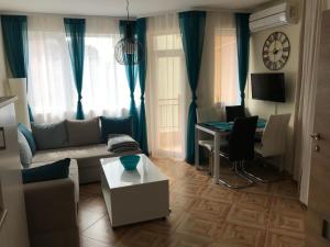 een woonkamer met een bank, een tafel en een klok bij Familienapartment am Strand in Primorsko in Primorsko
