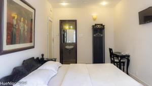een slaapkamer met een bed en een badkamer met een wastafel bij Hue Nino Hotel in Hue