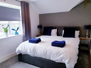um quarto com uma cama com toalhas azuis em Central Windermere Luxury two bed Apartment Dog Friendly em Windermere